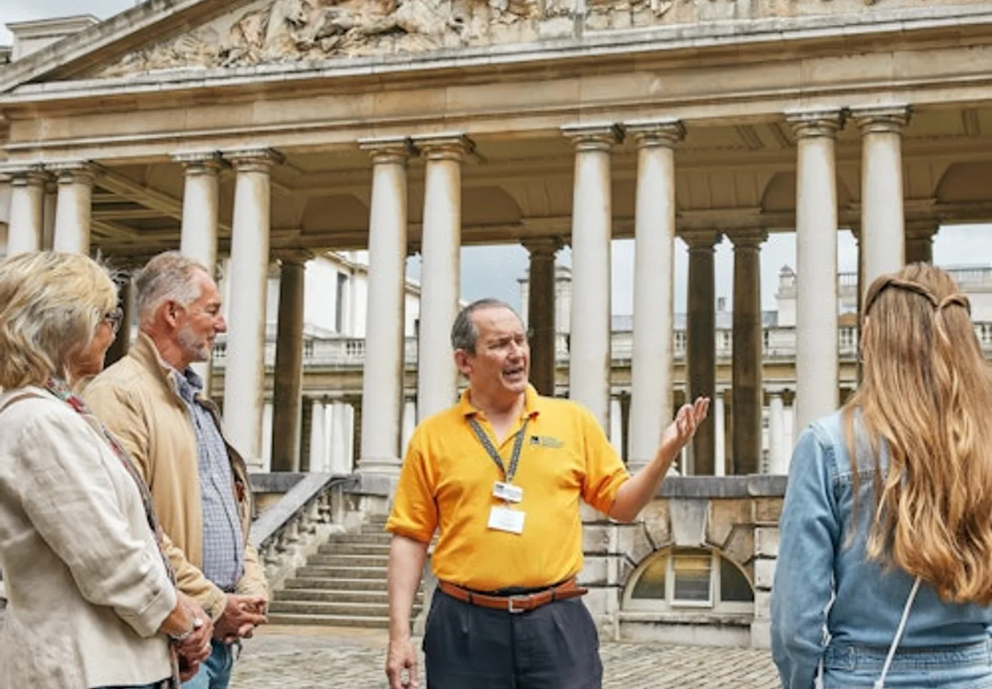 Visitors and guide beneath the Old Royal Naval College colonnades in Greenwich