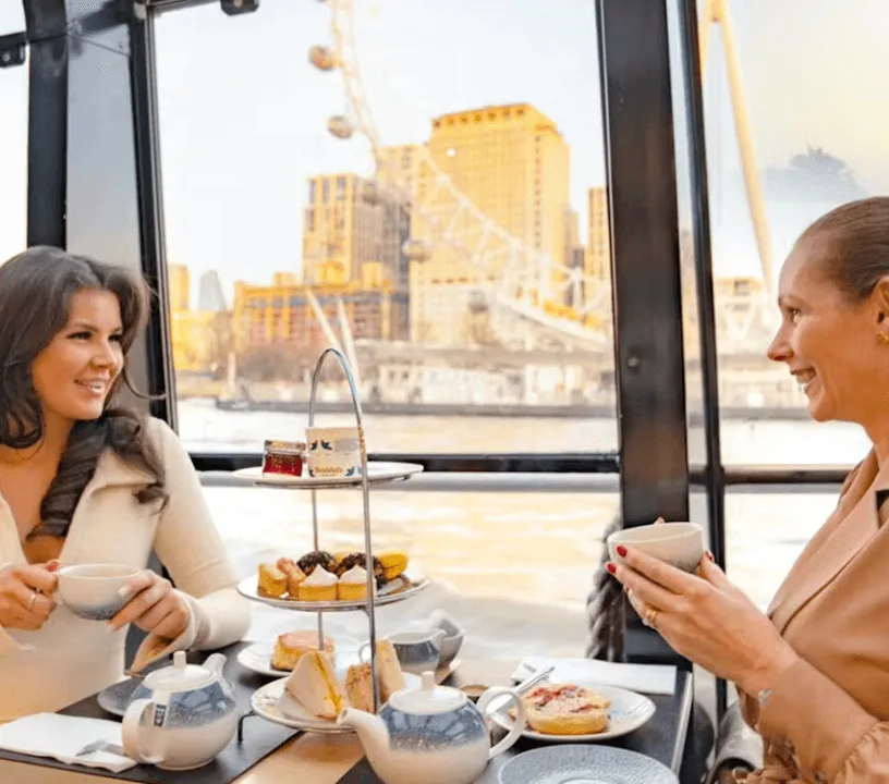 Guests dining beside the windows of a Thames cruise boat