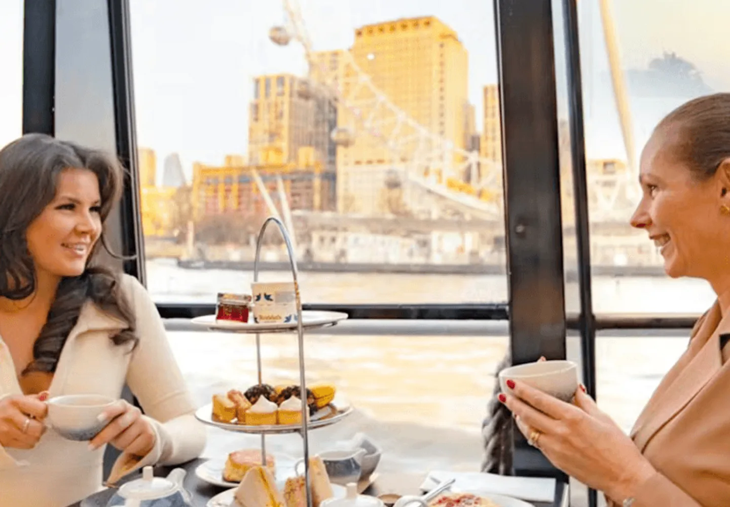 Guests dining beside the windows of a Thames cruise boat