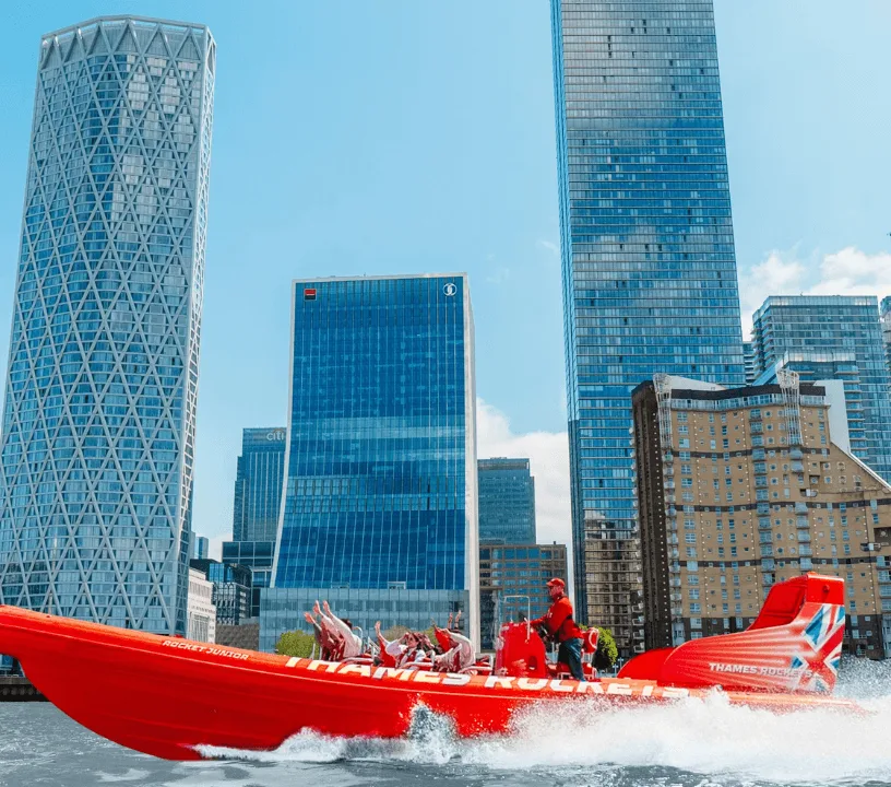 View across the bow of a red speedboat towards the London skyline