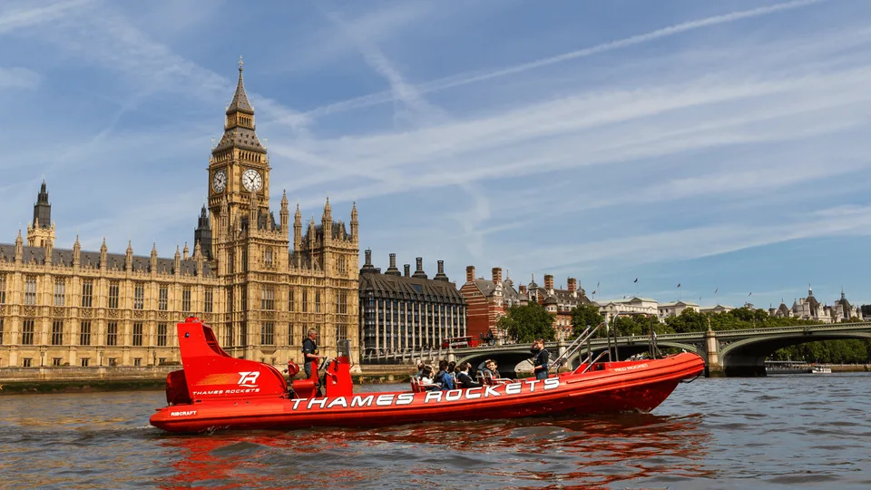 Red Thames speedboat passing the Houses of Parliament