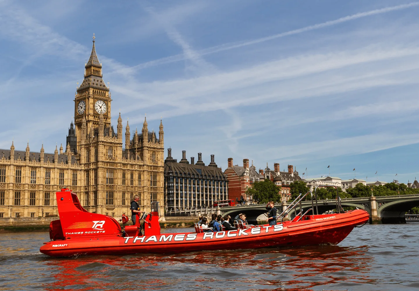 Red Thames speedboat passing the Houses of Parliament